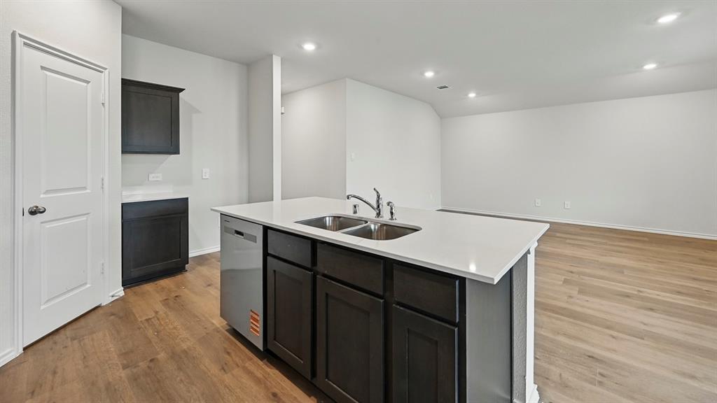 Kitchen island with dual stainless steel sinks, a chrome faucet, and a built-in dishwasher