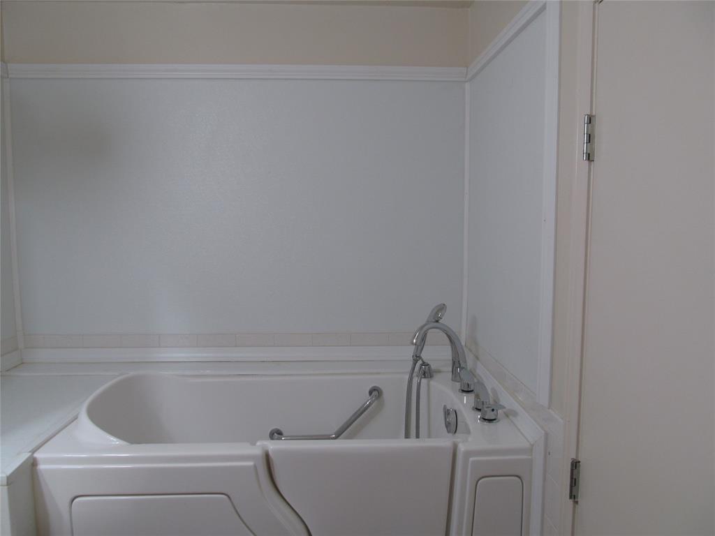 White walk-in bathtub with integrated grab bar and chrome fixtures