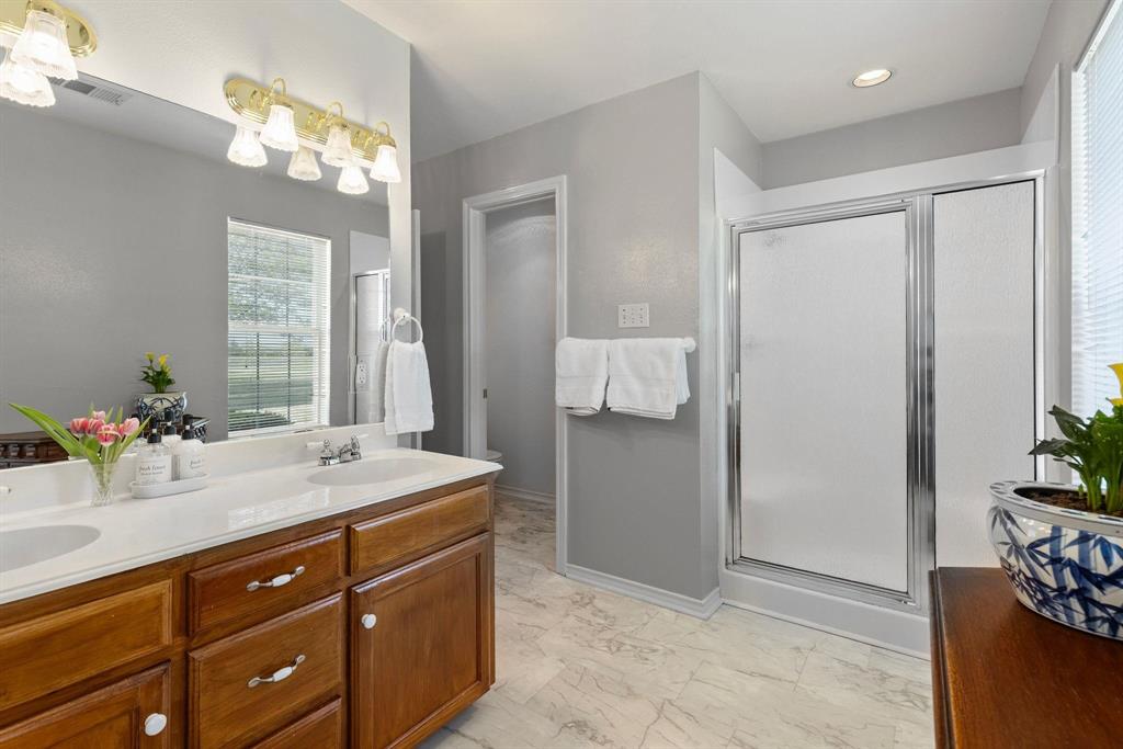 Bathroom featuring a dual vanity with wood-finish cabinetry, white countertop, and integrated sinks