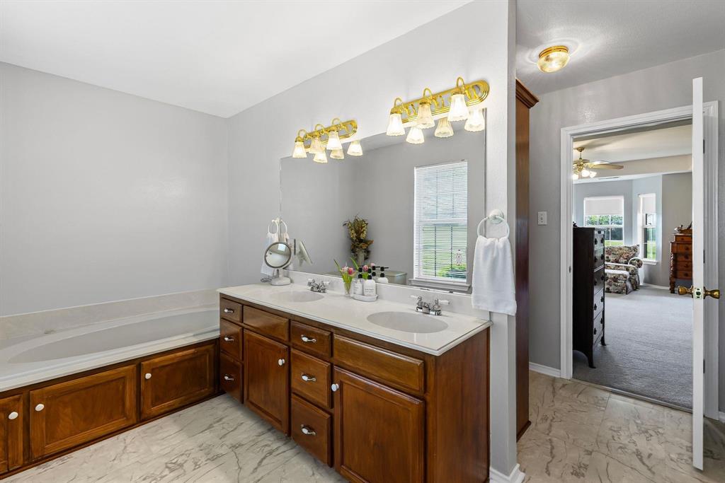 Bathroom featuring a dual-sink vanity with a light-colored countertop and wood-finish cabinetry