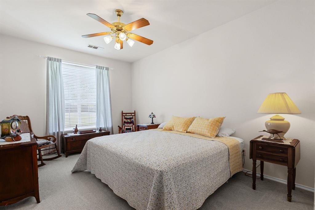 Carpeted bedroom featuring a ceiling fan with integrated lighting, a window with blinds, and white walls