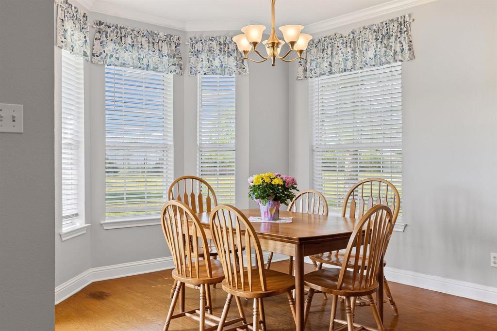 Bay window dining area featuring wood-finish flooring, light gray walls, and crown molding