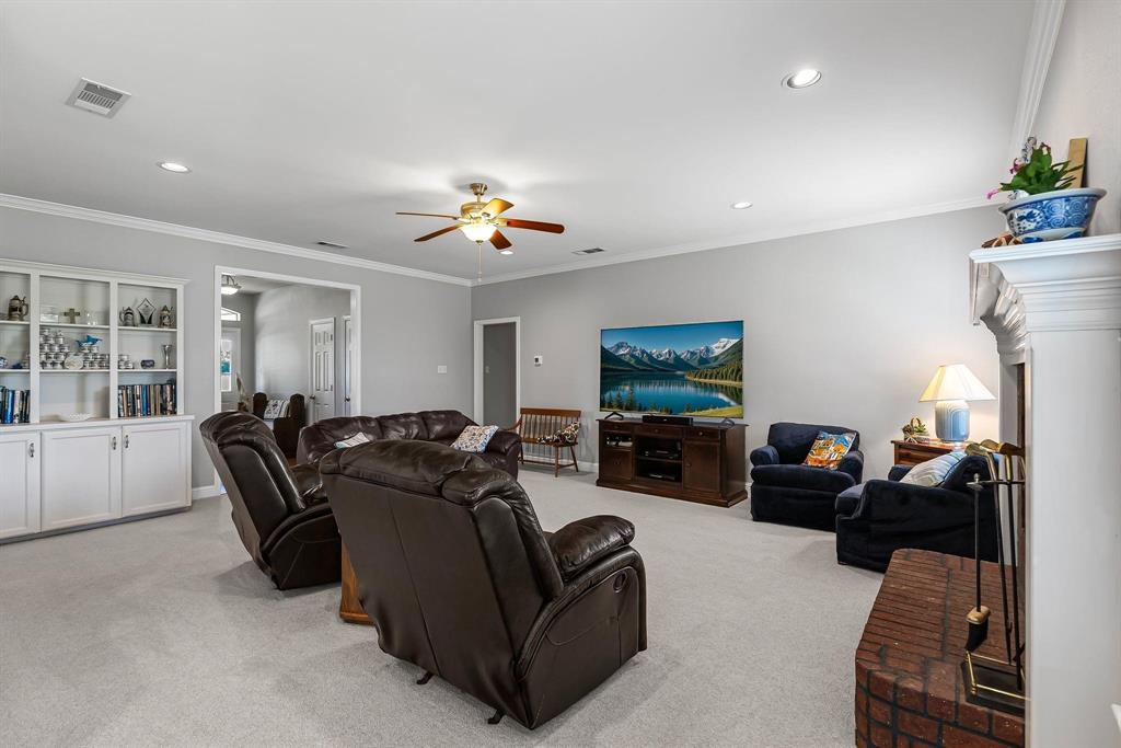 Spacious living area featuring light gray walls, white crown molding, recessed lighting, and a ceiling fan