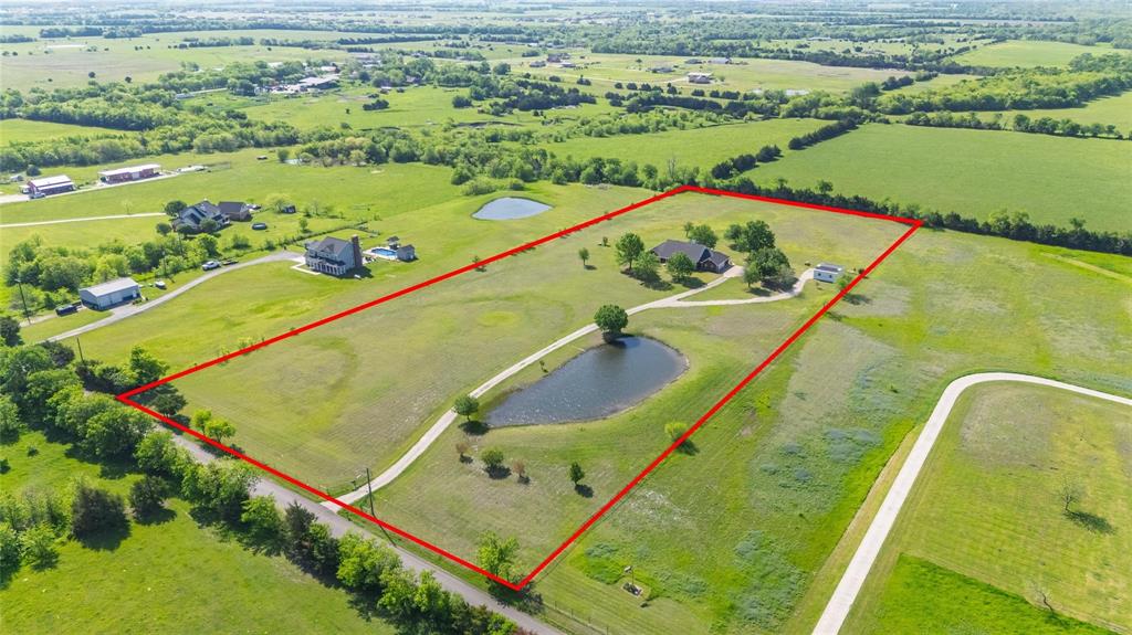 Expansive rural property featuring a main residence, additional structure, two private ponds, and extensive open green spaces