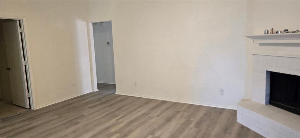 Living area featuring wood-finish flooring, a white-painted fireplace with a mantel, and two doorways