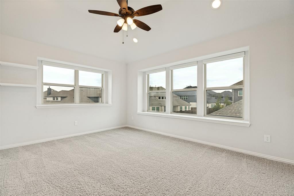 Carpeted room featuring multiple windows, a ceiling fan with integrated lighting, recessed lighting, and built-in shelving