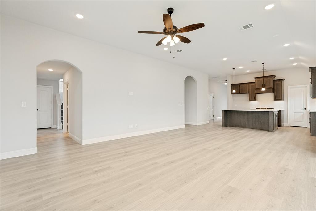 Spacious open-concept living area featuring light wood-finish flooring, recessed lighting, and an arched entryway
