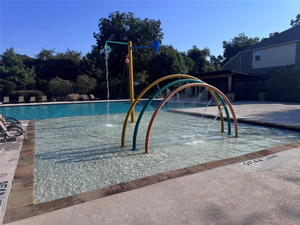 Community Pool area featuring a splash pad, main swimming pool, and pergola-covered patio