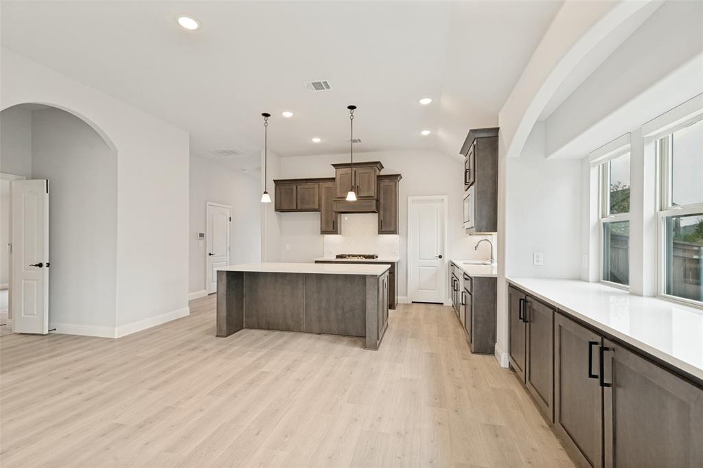Open-concept kitchen and living area featuring light wood-finish flooring, recessed lighting, and an arched doorway