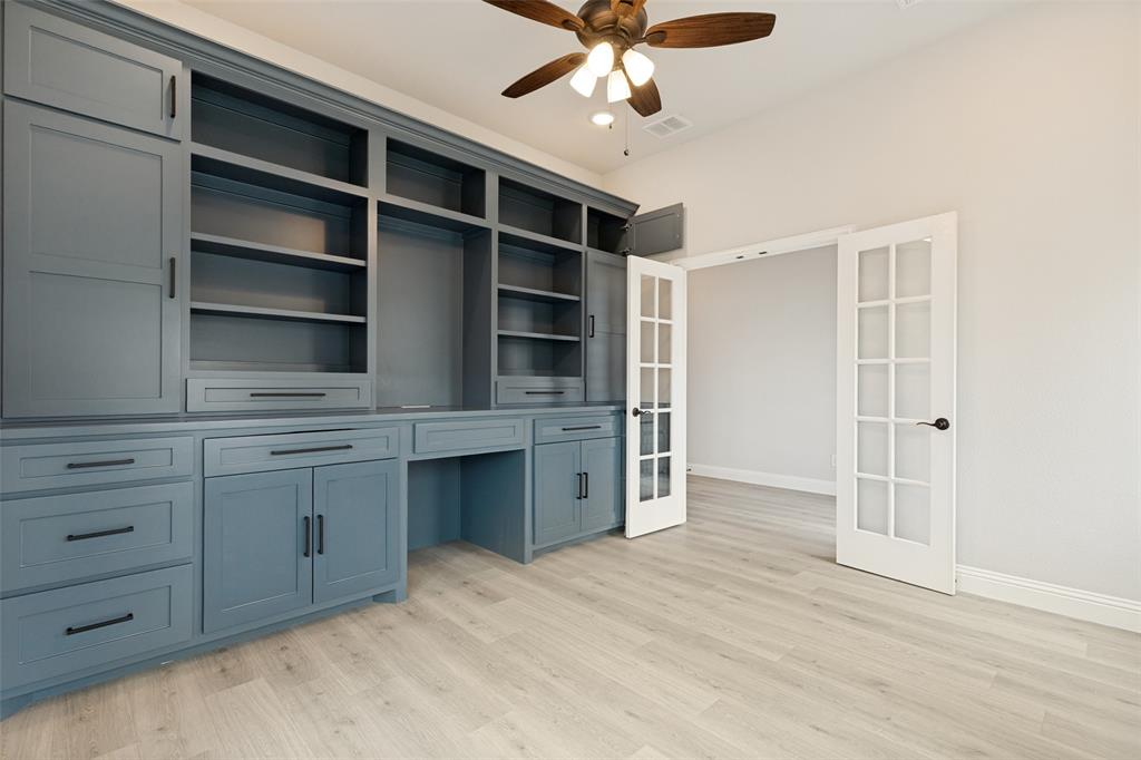 Built-in cabinetry in a muted blue finish featuring open shelving, enclosed storage, and desk space