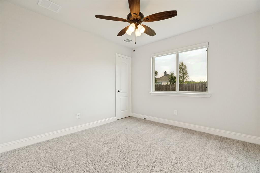 Bright interior space featuring light-colored carpet flooring, a multi-pane window, and a ceiling fan with integrated lighting