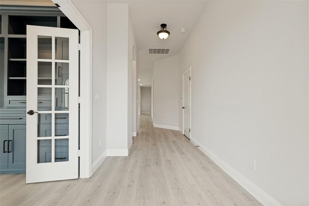 French doors with grid lites open to built-in cabinetry featuring open shelving and closed storage