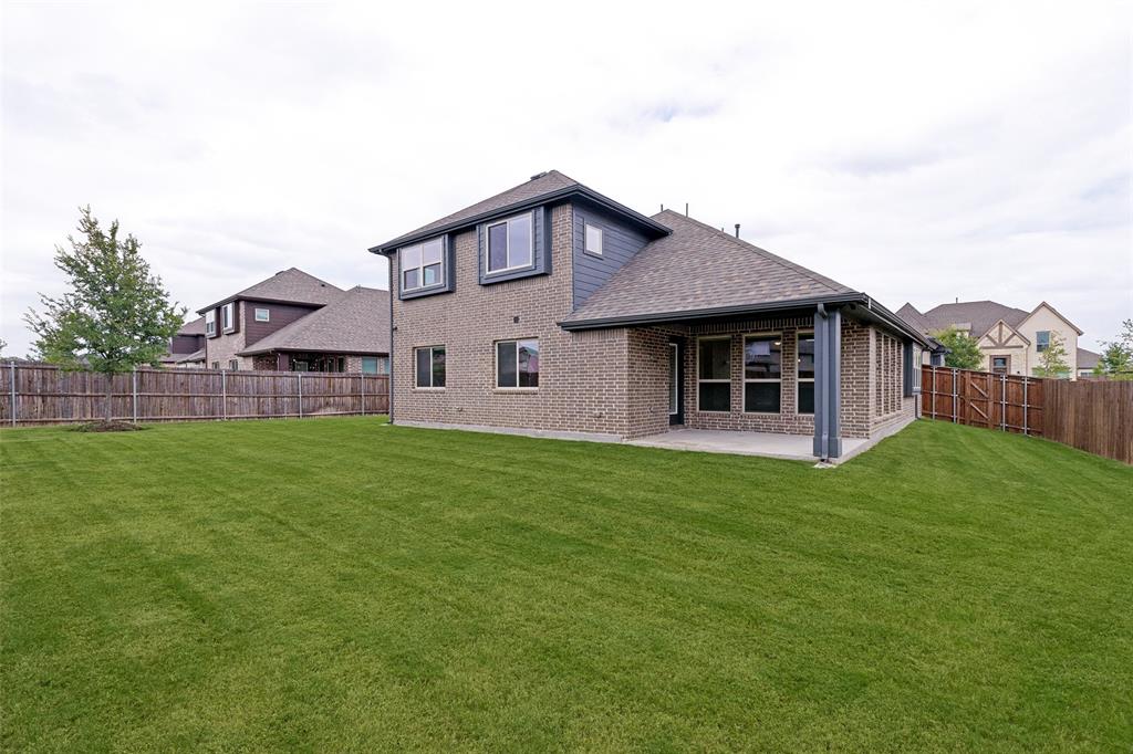 Spacious backyard featuring a brick exterior, covered patio, and wood privacy fencing