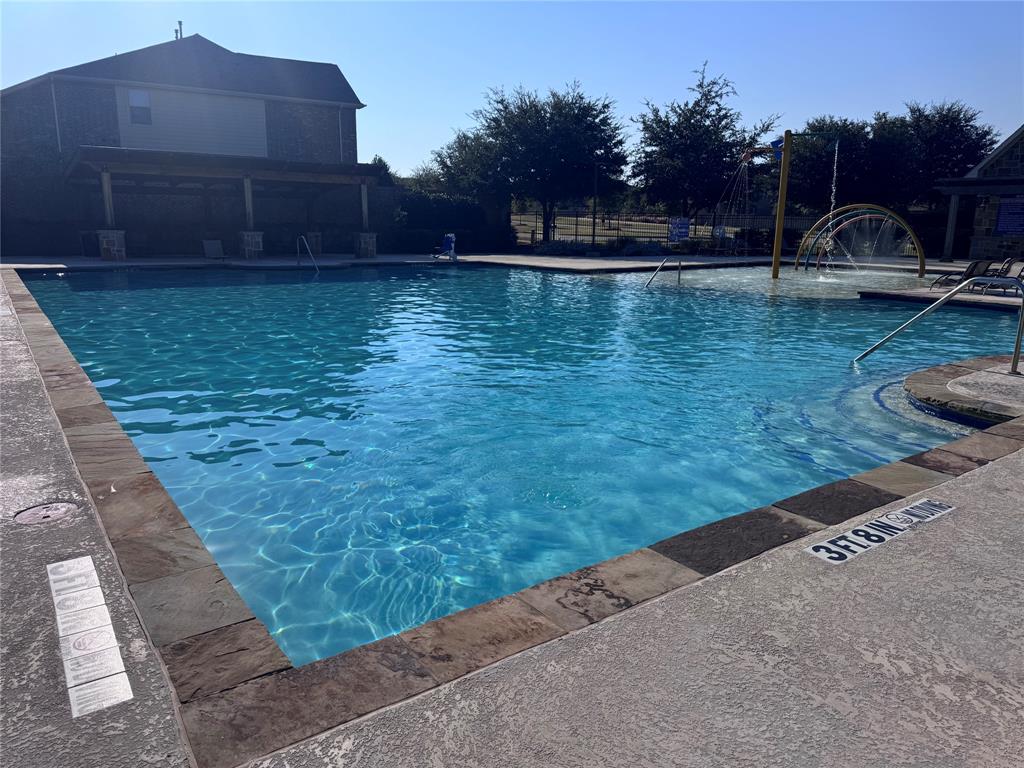 Community swimming pool featuring a shallow water play area, integrated water features, and a shaded pergola