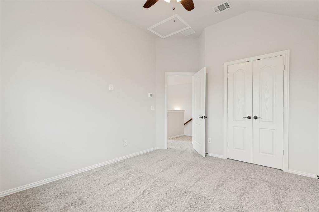 Room featuring a vaulted ceiling with a ceiling fan, light gray carpet, white baseboards, and a pair of white bifold doors with black hardware