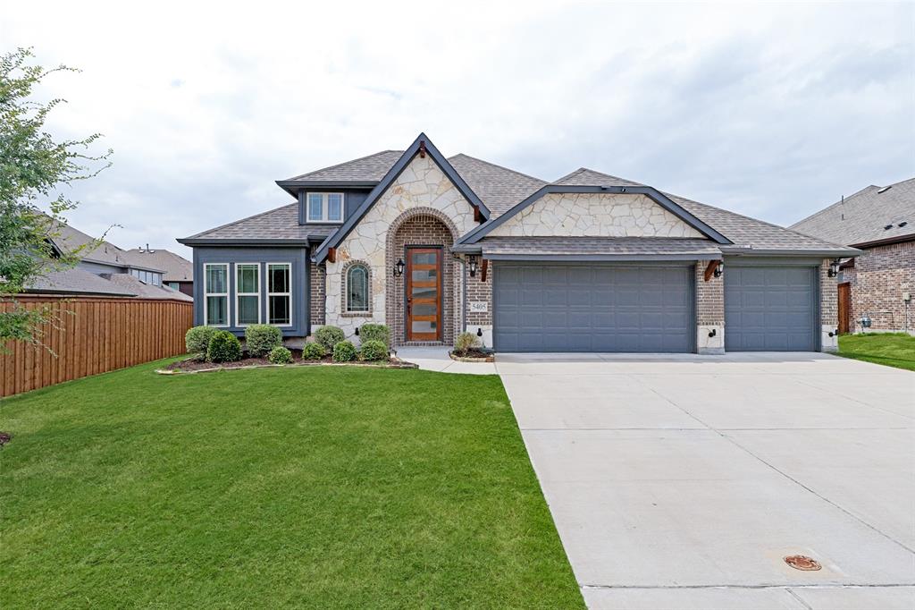 Stone and brick facade home featuring a multi-car garage, a concrete driveway, a wood-finish entry door, and manicured landscaping
