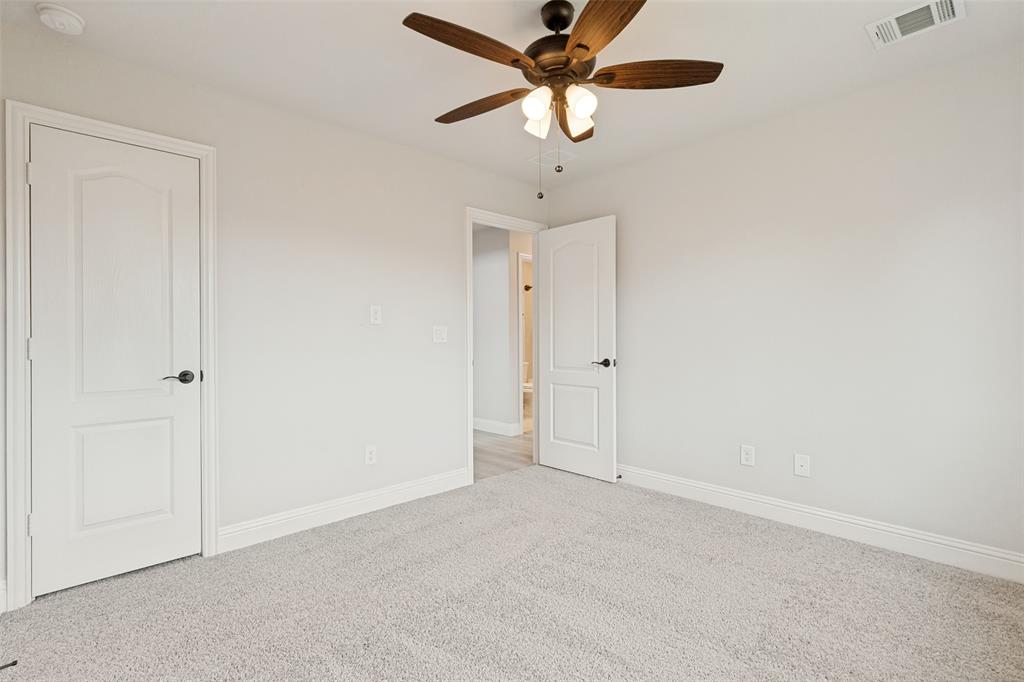 Neutral tone wall paint, light-colored carpeting, a dark wood-finish ceiling fan with integrated lighting, and white trim work