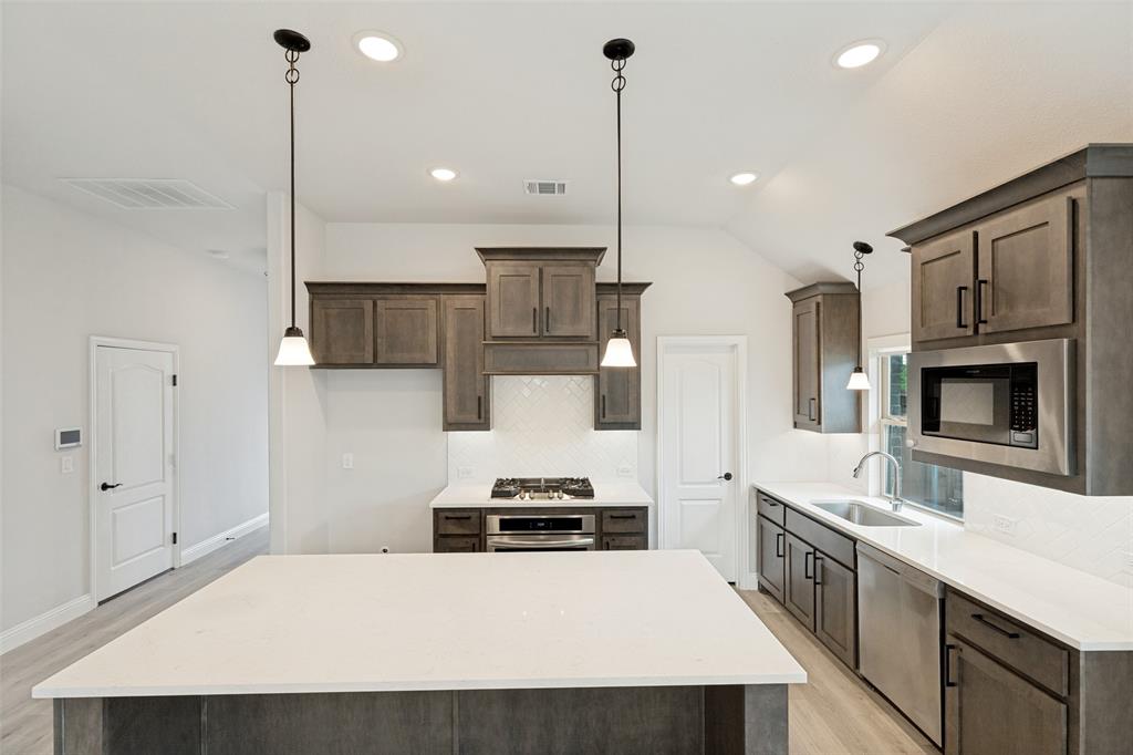 Spacious kitchen featuring an expansive island with a white countertop, wood-finish flooring, and recessed lighting