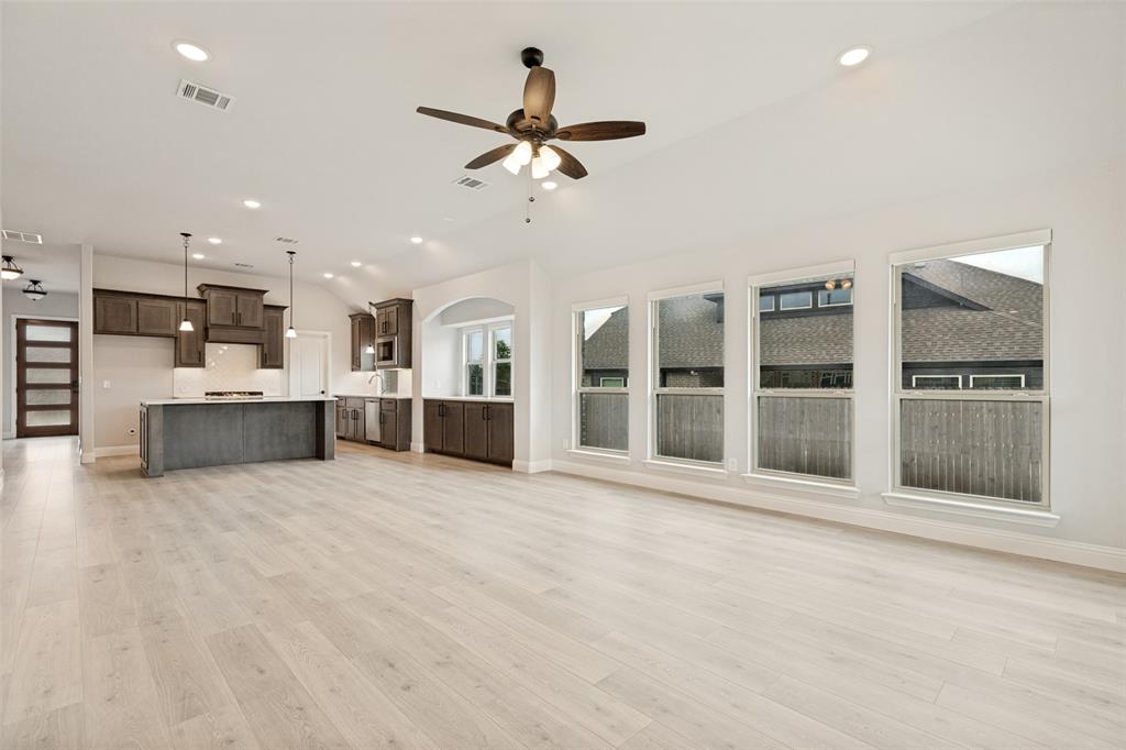 Bright open-concept living area featuring light wood-finish flooring, vaulted ceilings, and recessed lighting