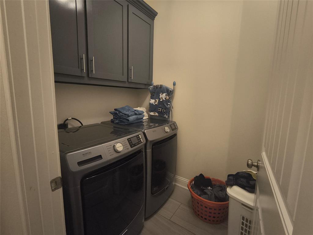 Dedicated laundry area featuring overhead cabinetry, tile flooring, and neutral wall tones