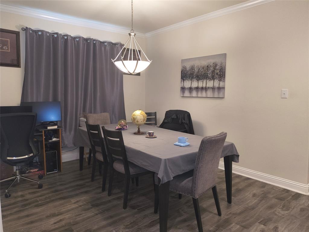 Spacious room featuring wood-finish flooring, crown molding, and baseboards