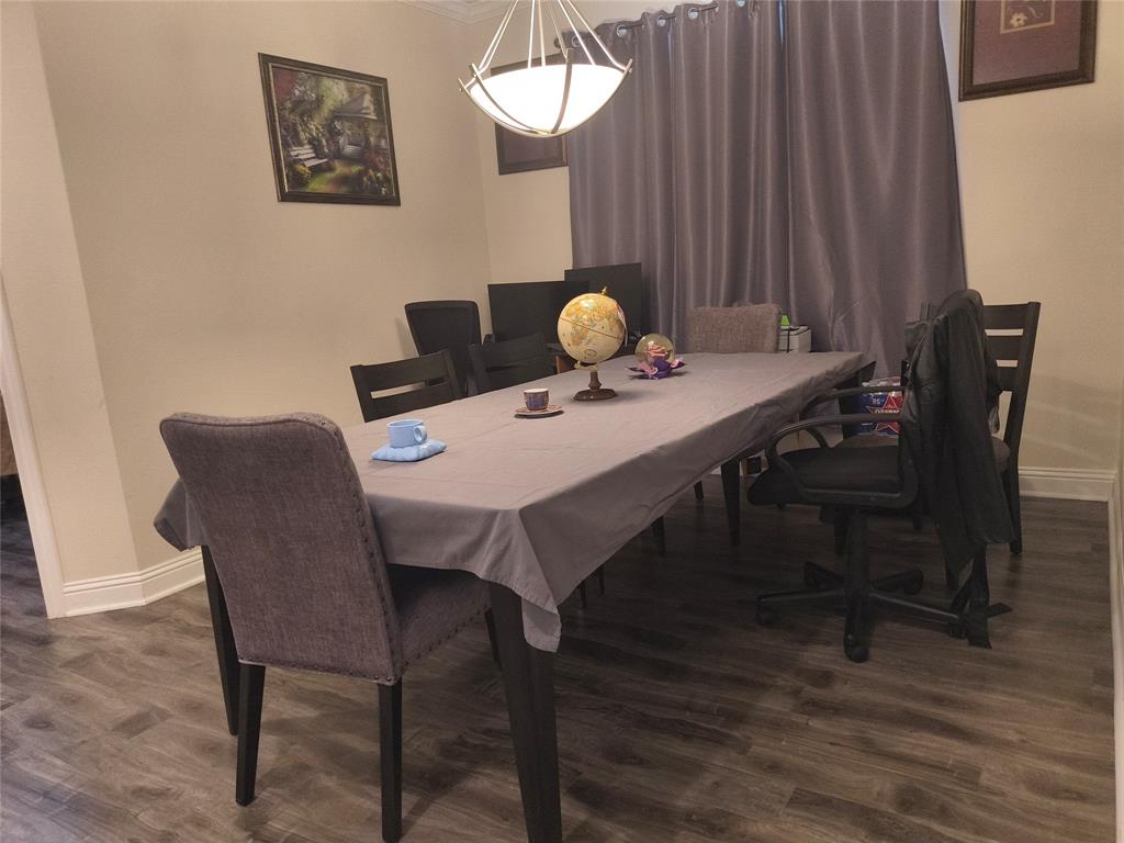 Dining area featuring wood-finish flooring, neutral wall tones, and crown molding