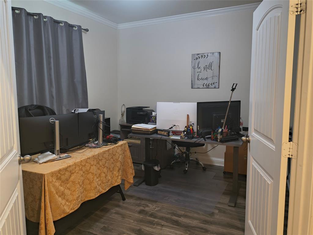 Interior room featuring wood-finish flooring, light-toned walls, and white crown molding