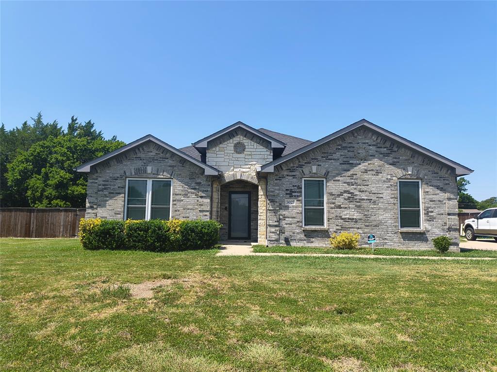 Single-story residence featuring a gray brick exterior with light stone accents, dark-framed windows, and a dark shingle roof Single-story residence featuring a gray brick exterior with light stone accents, dark-framed windows, and a dark shingle roof
