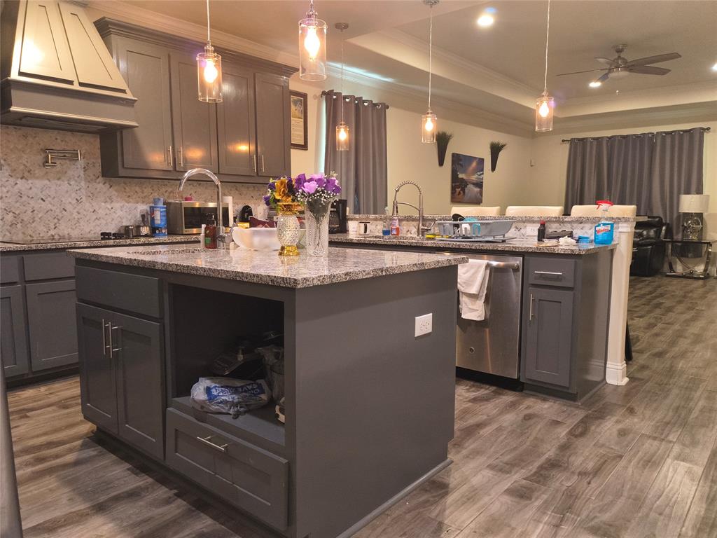 Kitchen featuring a large island with an undermount sink, granite countertops, and grey cabinetry