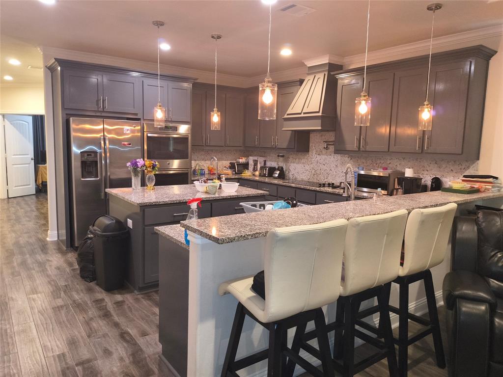 Kitchen featuring grey cabinetry, stainless steel appliances, granite countertops, and wood-finish flooring