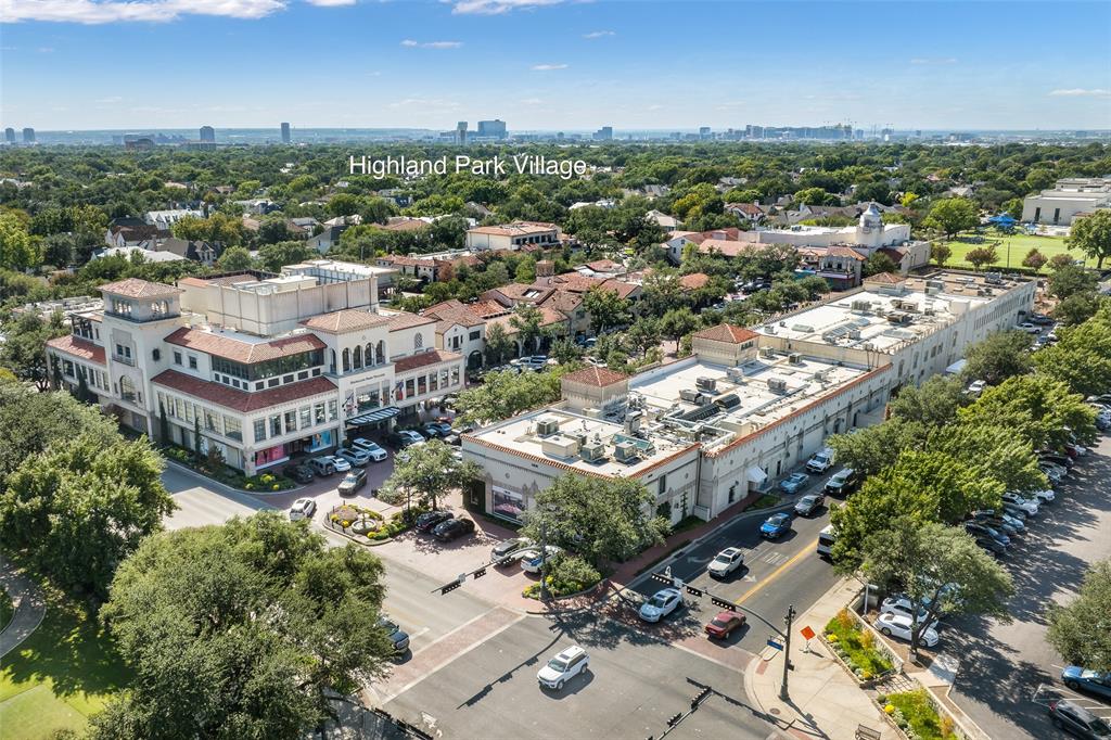 Aerial perspective of Highland Park Village featuring multi-level retail and office structures, Mediterranean-inspired architectural details, tile roofing, and paved surface parking