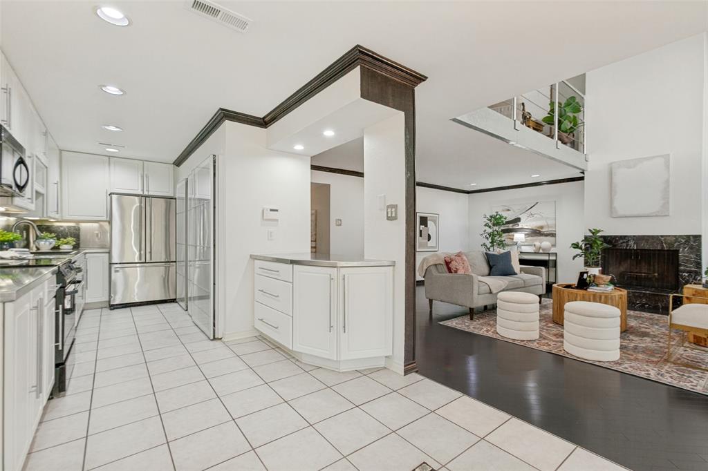 Galley kitchen featuring white cabinetry, stainless steel appliances, and tile flooring