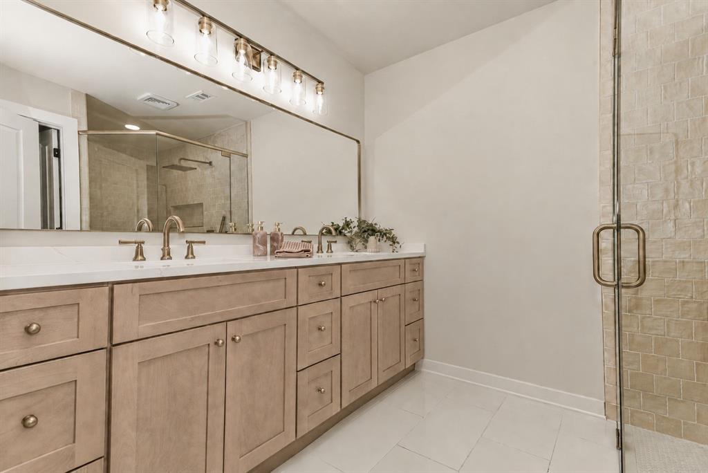 Double vanity with light wood-finish cabinetry, white countertop, and gold-finish fixtures