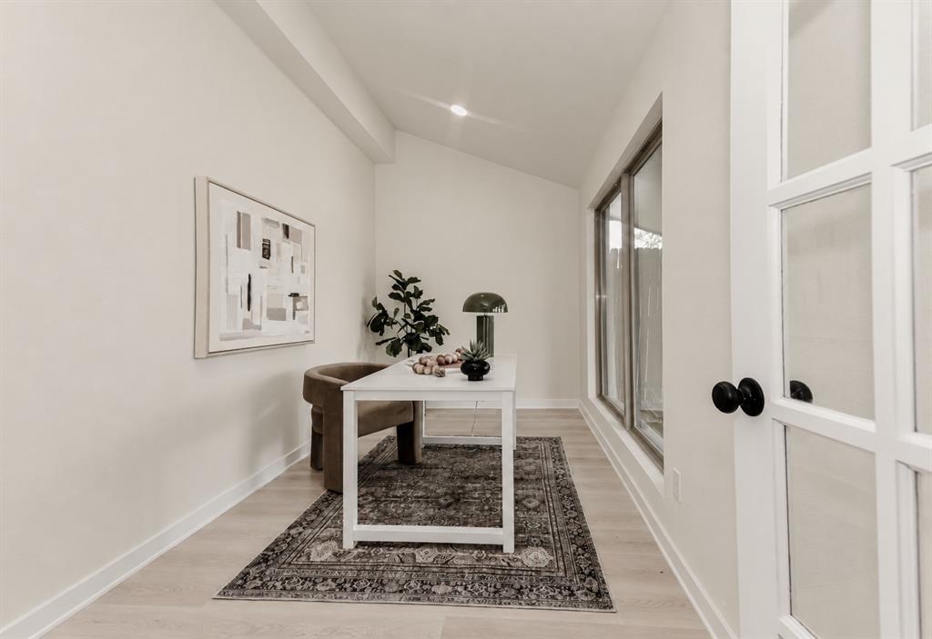 The office area has an expansive window array, wood-finish flooring, and a glass-paned door with black hardware