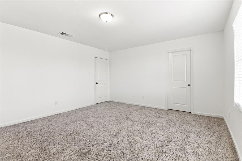 Spacious room featuring neutral carpeting, white painted walls, and white trim Spacious room featuring neutral carpeting, white painted walls, and white trim