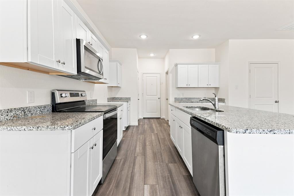 Contemporary kitchen featuring white cabinetry and granite countertops Contemporary kitchen featuring white cabinetry and granite countertops