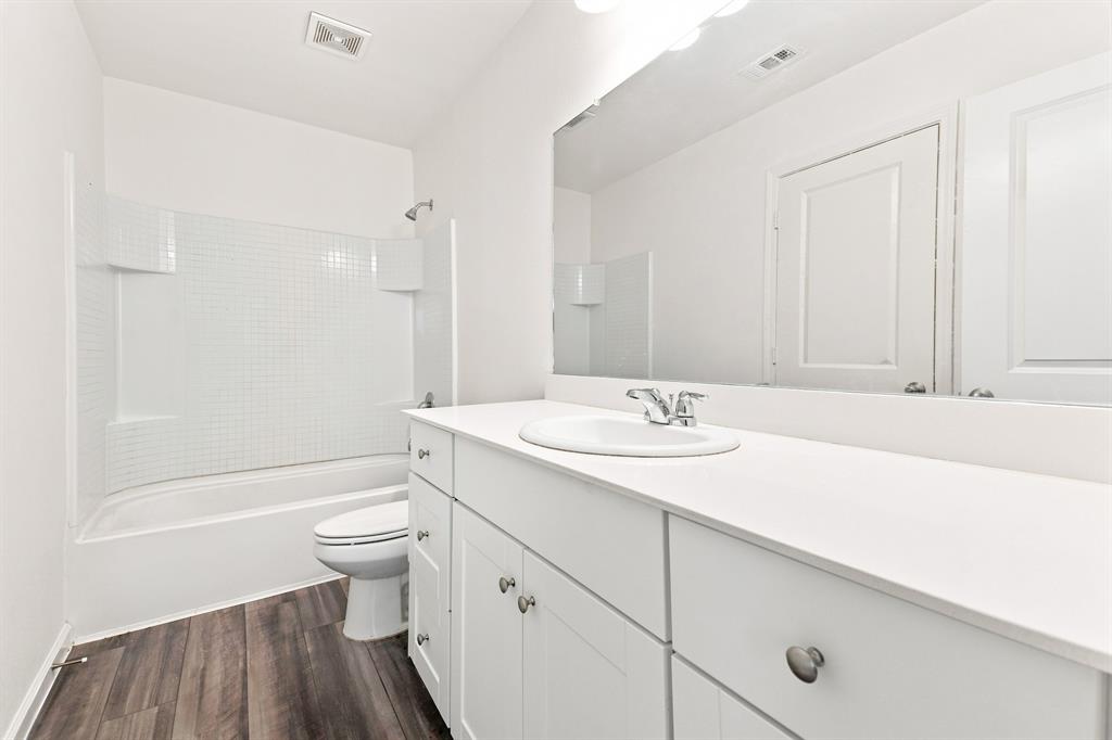 Bathroom featuring a white vanity with integrated sink, white countertop, and wood-finish flooring