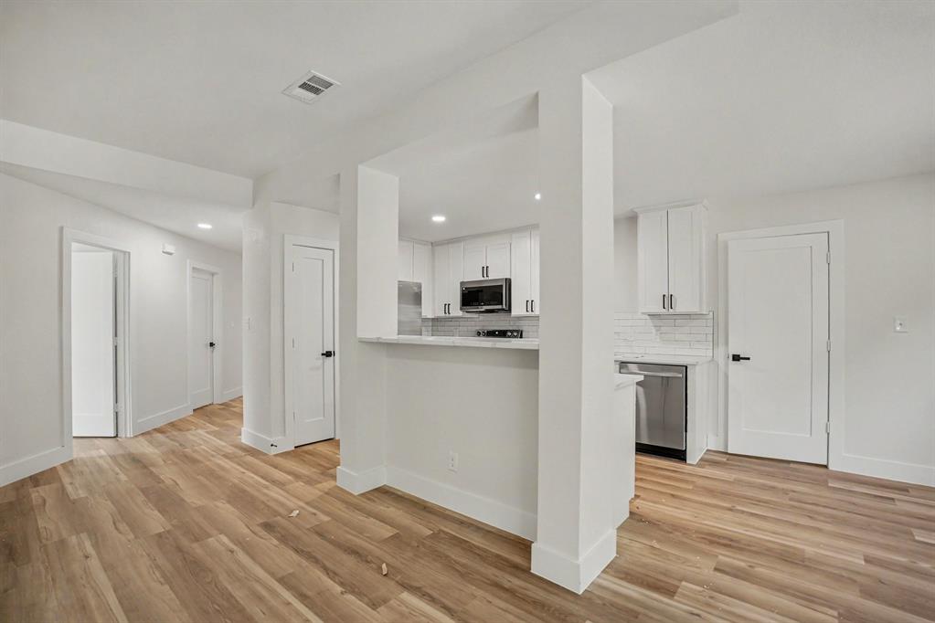 Kitchen area featuring white shaker cabinetry, stainless steel appliances, a subway tile backsplash, and a breakfast bar