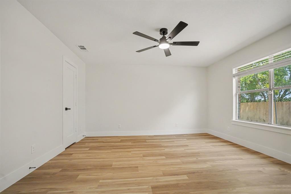 Spacious primary bedroom featuring wood-finish flooring, white walls, and a contemporary ceiling fan with integrated lighting