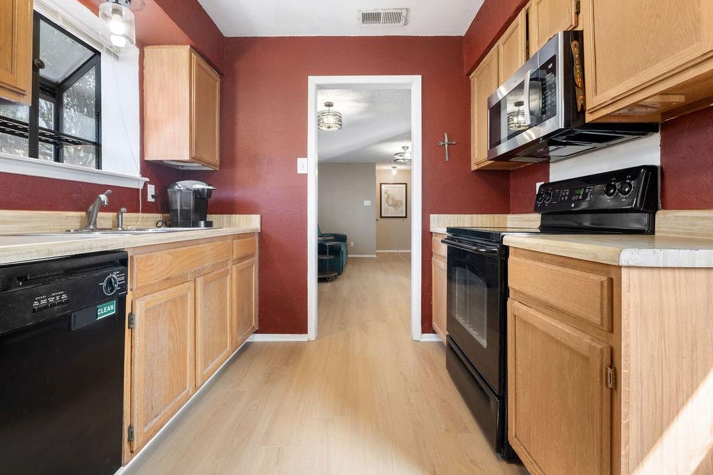 Galley kitchen with light wood-finish cabinetry, light wood-finish flooring, and light countertops Galley kitchen with light wood-finish cabinetry, light wood-finish flooring, and light countertops