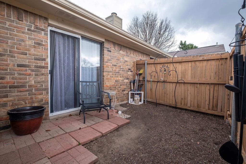 Private outdoor space featuring a red brick exterior, a sliding glass door, a paved patio area, and a wood privacy fence