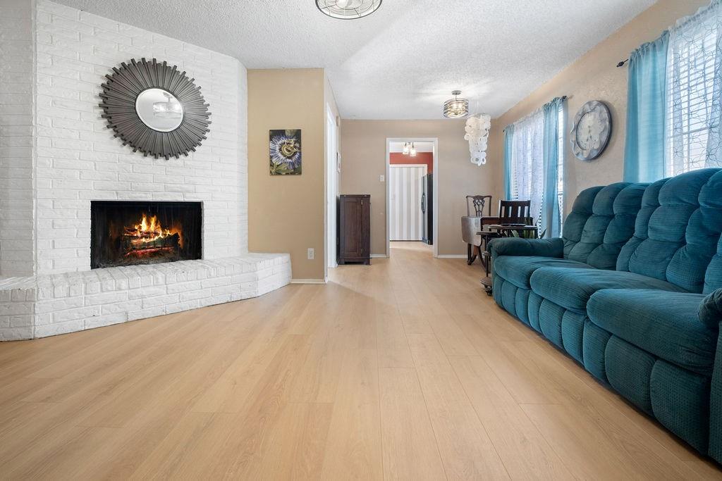 Living area featuring a painted brick fireplace, light wood-finish flooring, and recessed lighting Living area featuring a painted brick fireplace, light wood-finish flooring, and recessed lighting