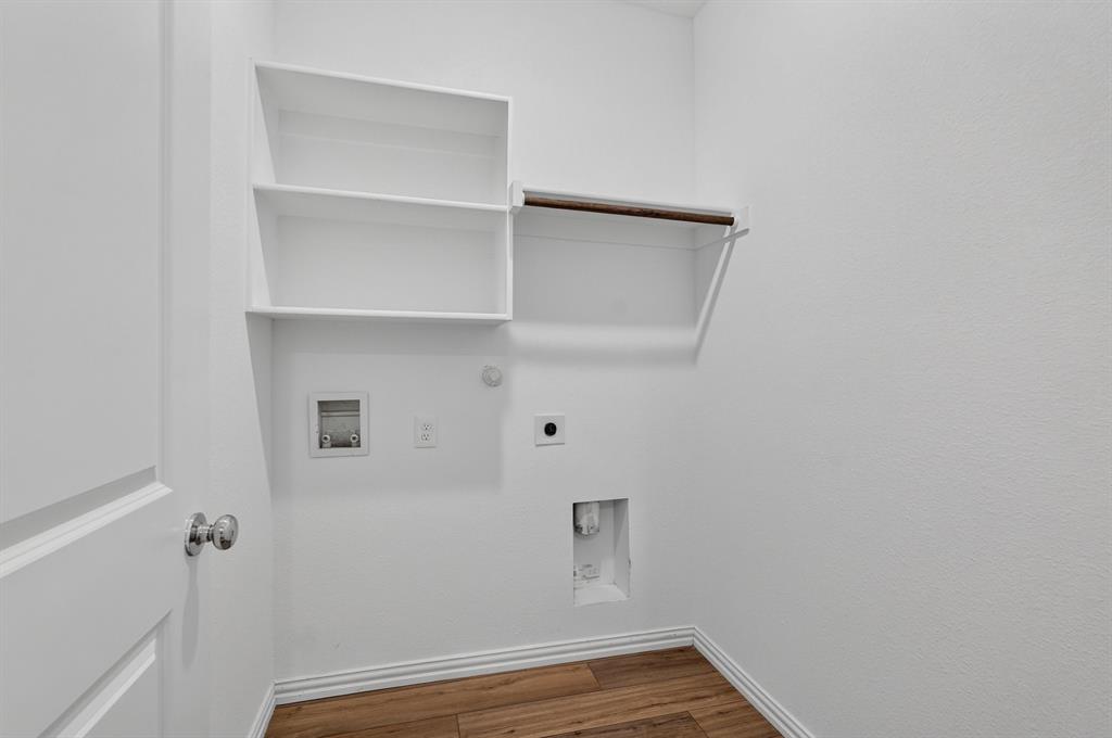 Utility area with white walls, wood-finish flooring, and white baseboards