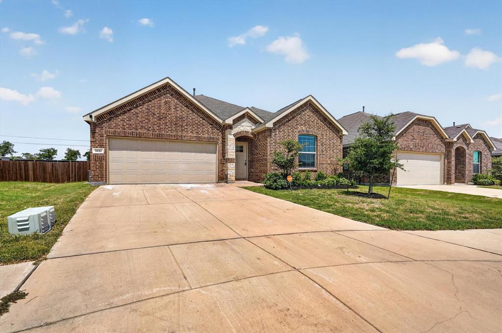 Welcoming brick exterior with a spacious two-car garage and expansive concrete driveway