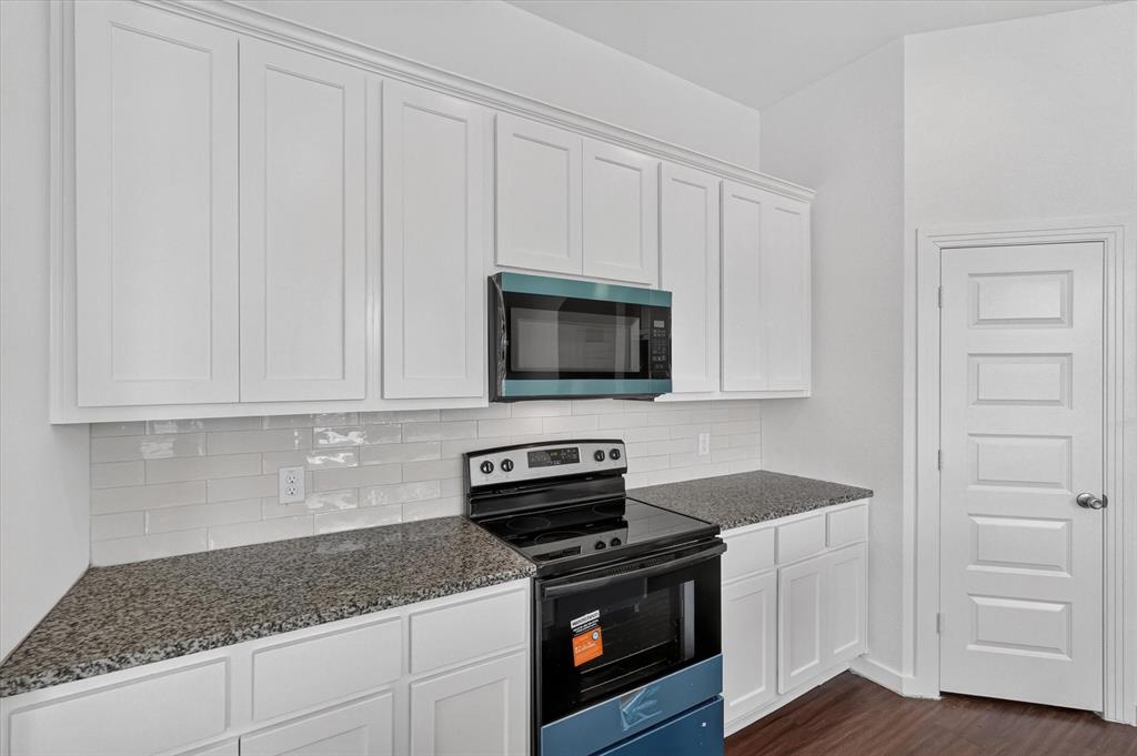 Kitchen featuring white shaker-style cabinetry, dark speckled countertops, and a white subway tile backsplash