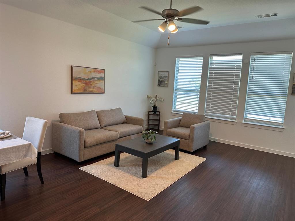 Tray ceiling with a ceiling fan, wood-finish flooring, and multiple windows with blinds