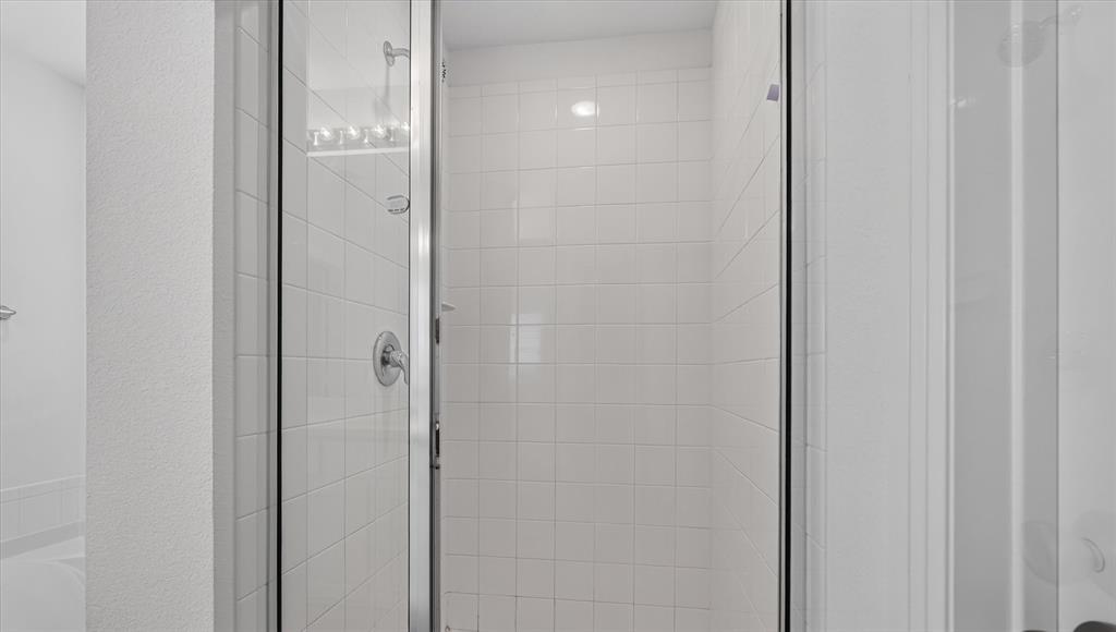 Spa-inspired shower enclosure featuring frameless glass doors, polished chrome hardware, and crisp white subway tile walls with integrated shelving for bath essentials