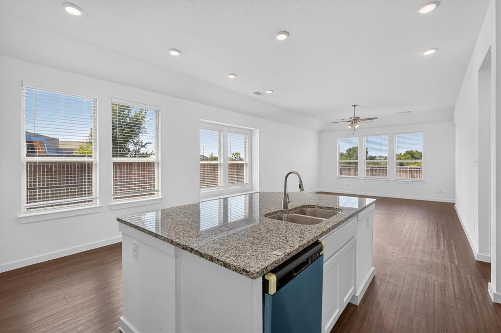 Chef's kitchen featuring a large center island with granite countertop, stainless steel sink with gooseneck faucet, white cabinetry, and dark blue island base