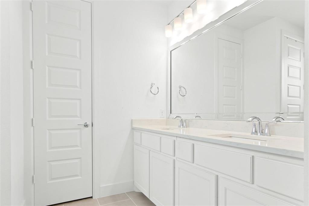 Dual vanity with white cabinetry, light-toned countertop, and chrome fixtures