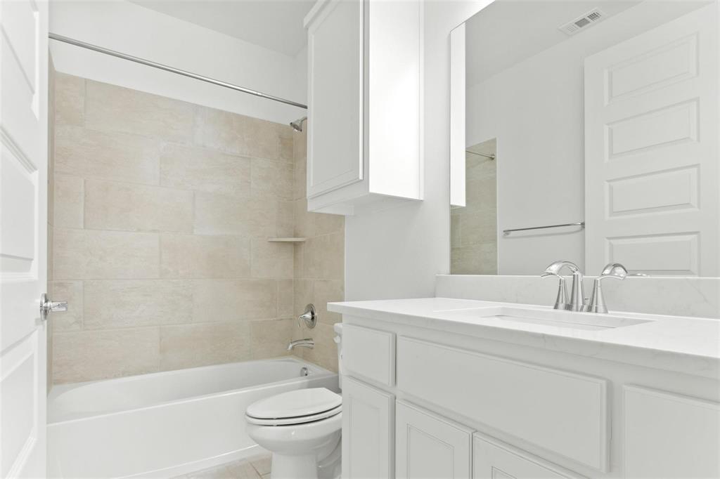 Bathroom featuring a white bathtub, light-toned tile surround with integrated shelf, and chrome fixtures